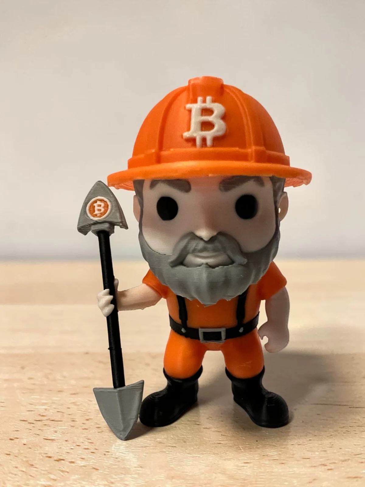 3D printed Bitcoin miner figure wearing an orange hard hat and holding a shovel